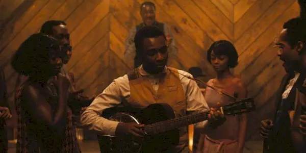 Miles Caton playing a musical instrument as other people look on in Ryan Coogler
