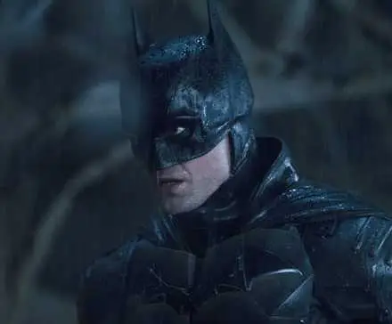 Robert Pattinson as Batman stares intently at something off-screen in The Batman.
