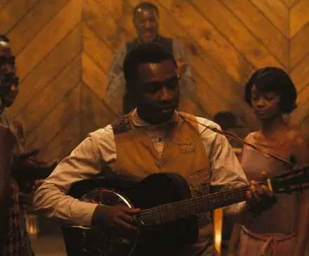Miles Caton playing a musical instrument as other people look on in Ryan Coogler