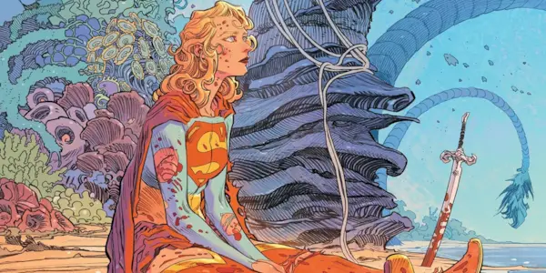 Supergirl sitting on a beach bloodied from battle in a DC comic book