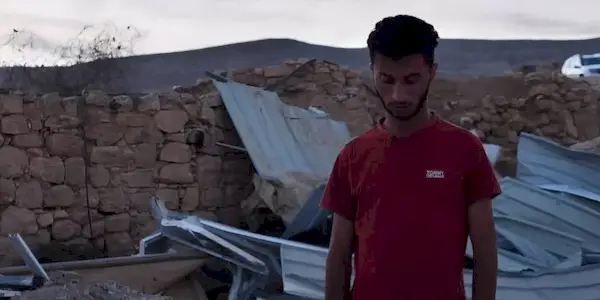 Basel Adra walking among rubble in No Other Land