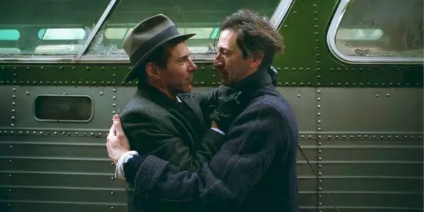 Adrien Brody and Alessandro Nivola hugging in front of a train in 