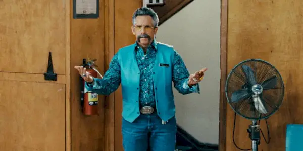 Hal L. in a blue paisley shirt and blue vest with his arm extended in Happy Gilmore 2.
