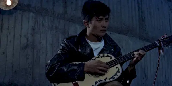 Akira Kobayashi playing the guitar in the evening as Shinji Taki in The Rambling Guitarist