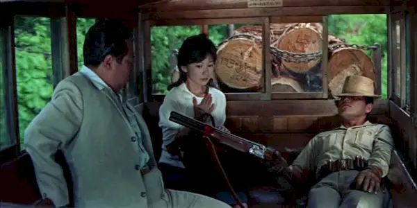 Hideaki Nitani pointing a shotgun at a man and a woman in a carriage in Man With a Shotgun