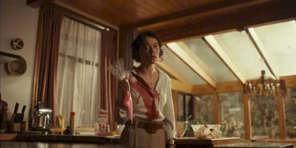 Tatiana Maslany covered in blood holding icing while in the kitchen in The Monkey.