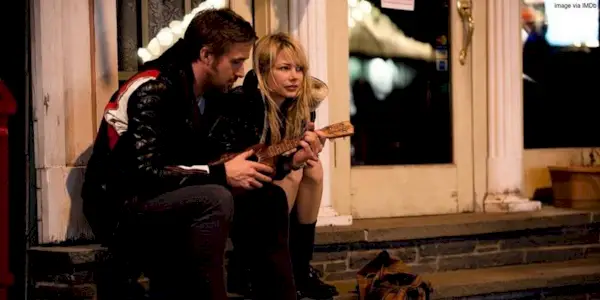 Cindy and Dean talking while sitting on a set of stairs on the street in Blue Valentine