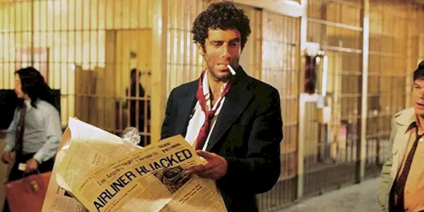 Philip Marlowe smoking while holding a newspaper in prison in The Long Goodbye