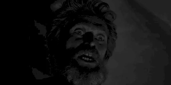 A close-up shot of Thomas Wake looking terrified in The Lighthouse.