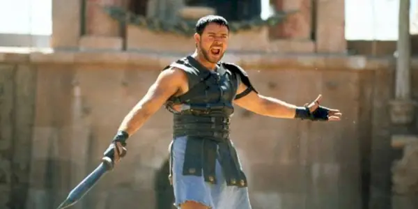 Maximus yelling and spreading his arms while holding a sword in Gladiator