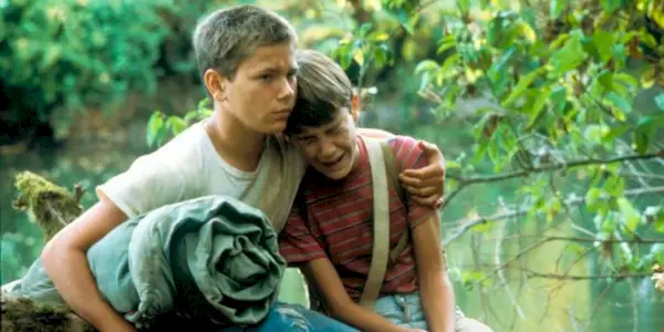 River Phoenix as Chris consoles his upset friend, Wil Wheaton as Gordie, in the woods