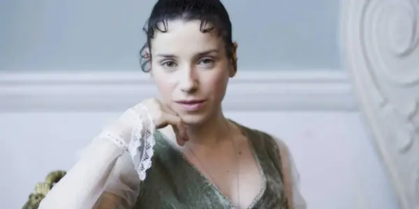 Sally Hawkins as Anne in Persuasion looking at the camera and smiling while sitting down.