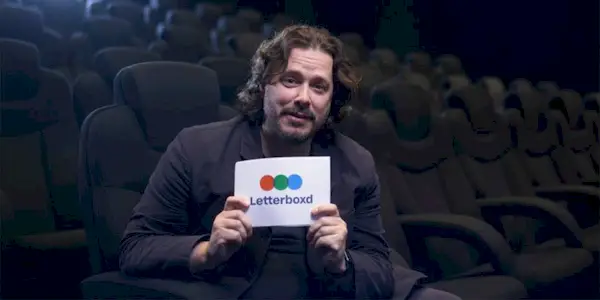 Edgar Wright sitting in a movie theater holding a letterboxd card