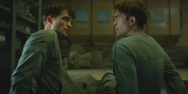 Robert Pattinson as two Mickey clones lying on a bed looking shocked to see each other.