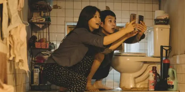 Park So-dam and Choi Woo-shik check their cellphones in a scene from Parasite