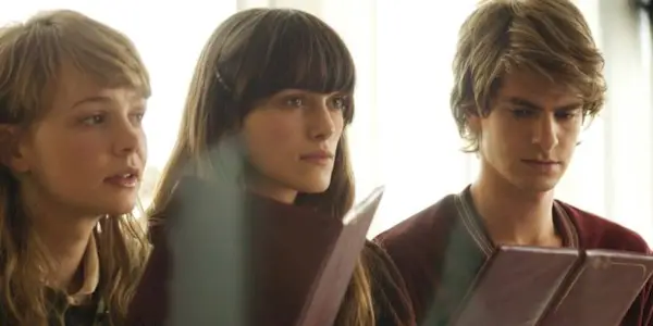 Keira Knightley, Carey Mulligan, Andrew Garfield sitting together in Never Let Me Go.