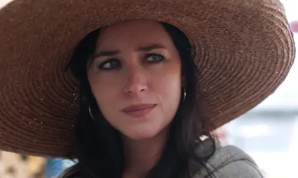 Dakota Johnson as Nina wearing a hat in The Lost Daughter