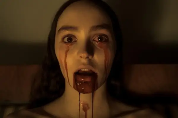 Lily Rose Depp as Ellen Hutter in Nosferatu with blood pouring out of her eyes. The words 