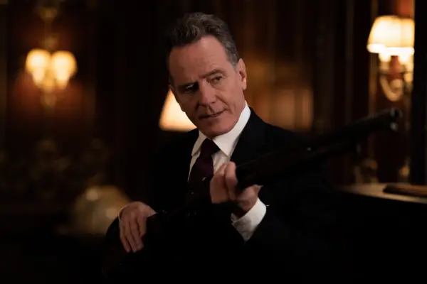 Bryan Cranston as Ritter in Argylle. He is wearing suit and tie and holding a gun