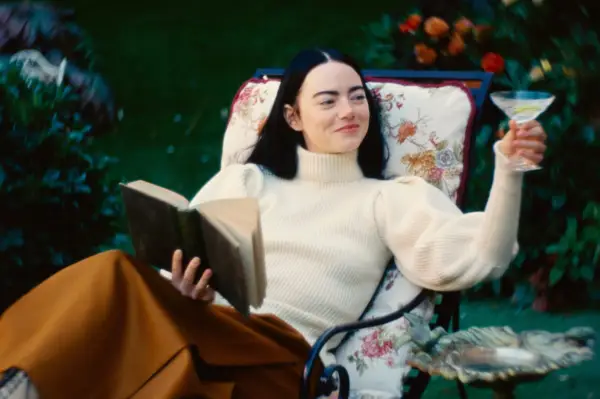 Emma Stone as Bella Baxter in Poor Things sitting on a lounger holding a book