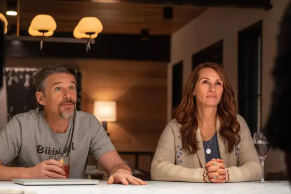 Ethan Hawke as Clay and Julia Roberts as Amanda in Leave the World Behind sitting at a table.