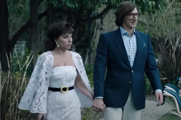 Lady Gaga and Adam Driver walking together in formal attire, holding hands