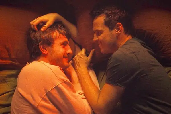 Paul Mescal as Harry lying on a bed face to face with Andrew Scott as Adam with Scott