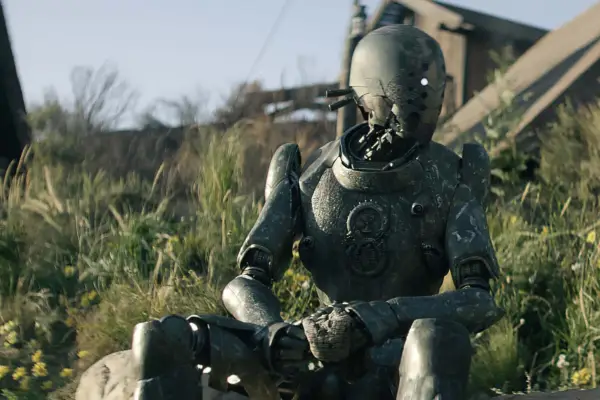 Jimmy sits on a grassy hill, looking to their left hand side