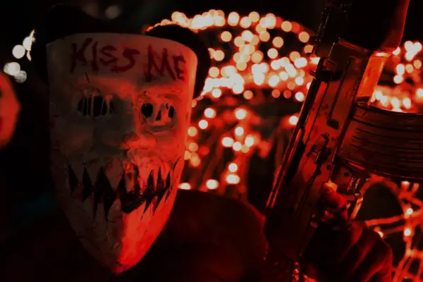 Brittany Mirabile in The Purge: Election Year wearing a mask that says Kiss Me