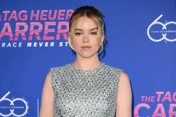 Milly Alcock posing for a picture on the red carpet. She is wearing a silver dress.