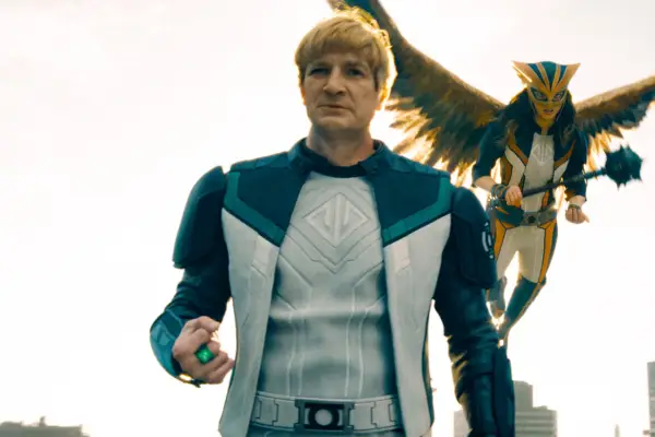 Nathan Fillion stars as Guy Gardner aka Green Lantern in Superman, wielding a power ring on a rooftop with Hawkgirl flying behind him