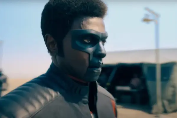 Edi Gathegi plays Mister Terrific in Superman, looking serious at someone or something ahead of him. He is wearing his famous 