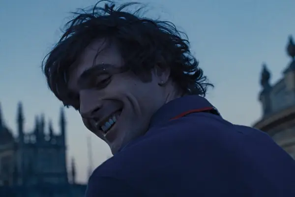 Jacob Elordi turns over his shoulder and smiles as Felix Catton on the roof of Oxford University at dusk in Saltburn.