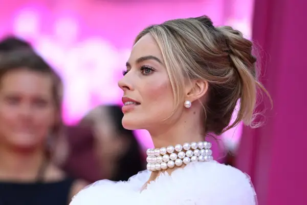 Margot Robbie attends the premiere of Barbie, wearing a pearly necklace and white dress