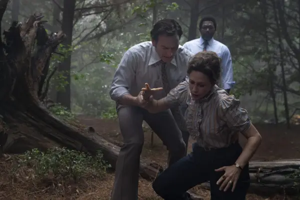 Vera Farmiga and Patrick Wilson in The Conjuring: The Devil Made Me Do It looking panicked in a wooded area