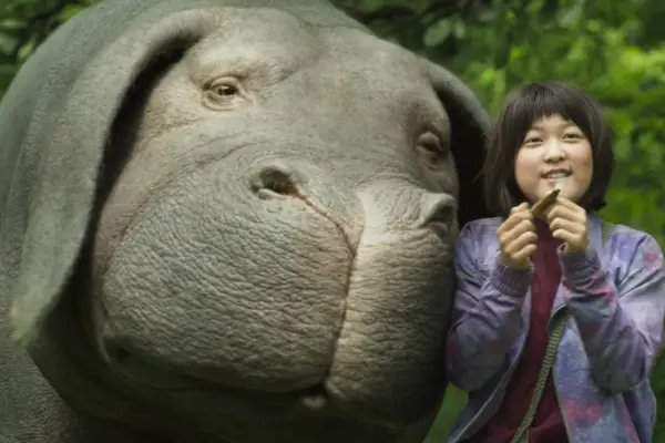 Okja still showing a girl next to a hippo-like creature
