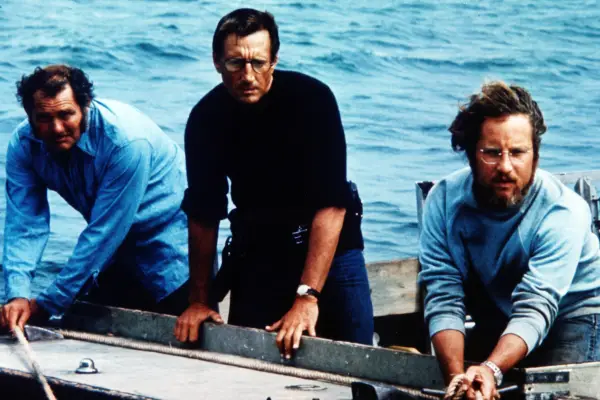 As still from the film The Iron Claw showing Zac Efron as Kevin, Holt McCallany as Fritz, Harris Dickinson as David and Jeremy Allen White as Kerry playing American football on some grass