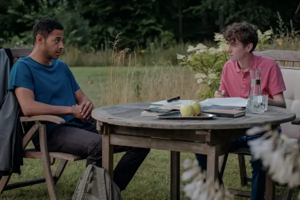 Daryl McCormack as Liam and Stephen McMillan as Bertie sitting at a wooden table in The Lesson