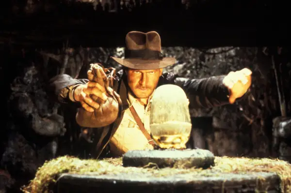 Harrison Ford in Raiders of the Lost Ark, holding a sack and approaching an artefact