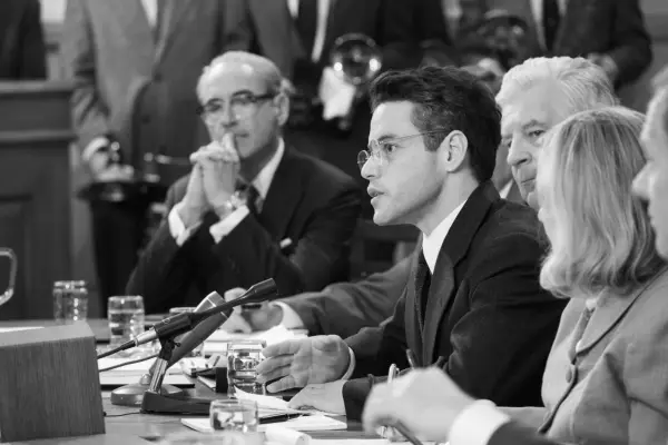 Rami Malek as David Hill, wearing a suit and glasses