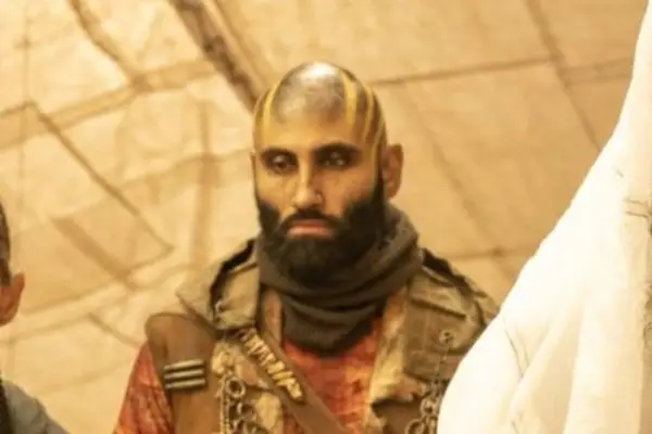 Matuse as Fang in Furiosa: A Mad Max Saga wearing a scarf and brown outfit