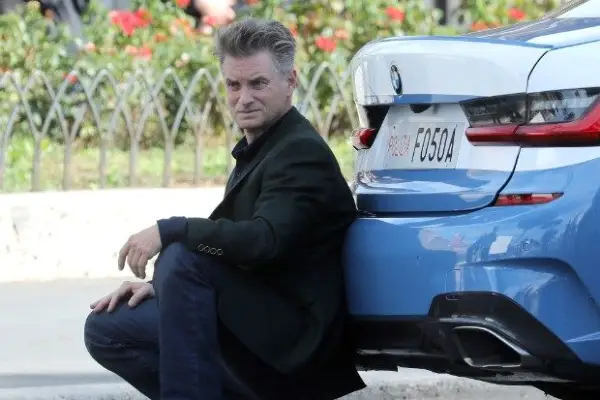 Shea Whigham is seen filming Mission Impossible 7 at Via Dei Fori Imperiali, crouching behind a police car