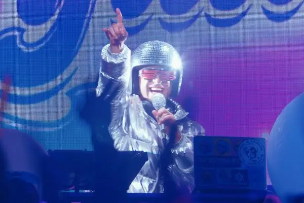 Ido Mosseri plays DJ Schmuley in You Are So Not Invited to My Bat Mitzvah wearing an all-silver outfit, holding a microphone and pointing to the sky