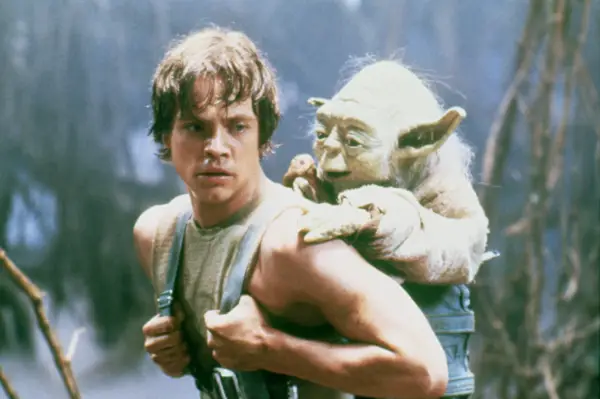 Mark Hamill on the set of Star Wars: Episode V The Empire Strikes Back with the puppet of Yoda on his back.