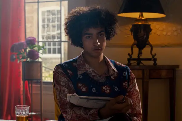 Archie Madekwe as Farleigh Start in Saltburn wearing a flowery jumper and shirt