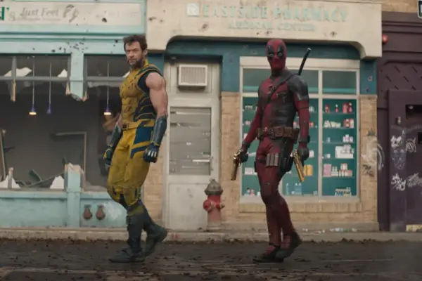 Hugh Jackman in a yellow Wolverine suit and Deadpool in a red suit walking together