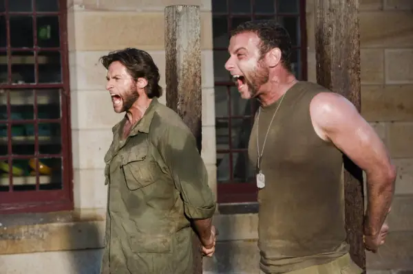 Hugh Jackman and Liev Schreiber tied to posts, screaming