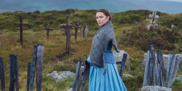 Lib, wearing a bright blue dress and standing in a graveyard in 