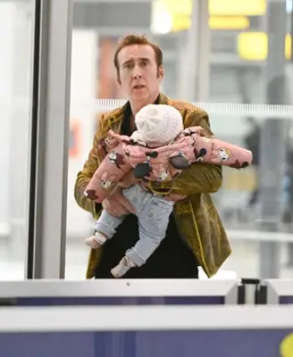 Nicolas Cage, de 59 años, sonríe mientras lleva a una hija de siete meses con su esposa Riko Shibata, de 28 años, en el aeropuerto de JFK