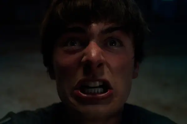 Noah Schnapp as Will Byers in Stranger Things looking upwards and gritting his teeth in anger.